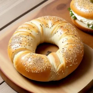 Freshly baked sourdough bagel with a golden-brown crust, topped with cream cheese, smoked salmon, and avocado on a wooden surface.